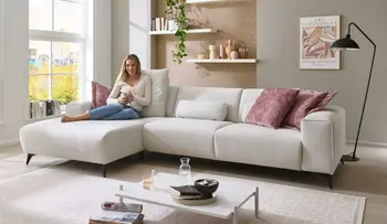 Frau sitzt auf gemütlichen weißem Sofa und entspannt.